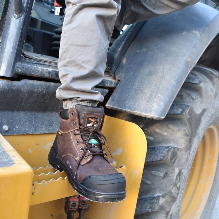 Person wearing a brown work boot on a piece of heavy machinery.