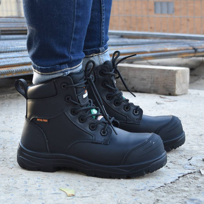 Black boots worn with blue jeans on a construction site background