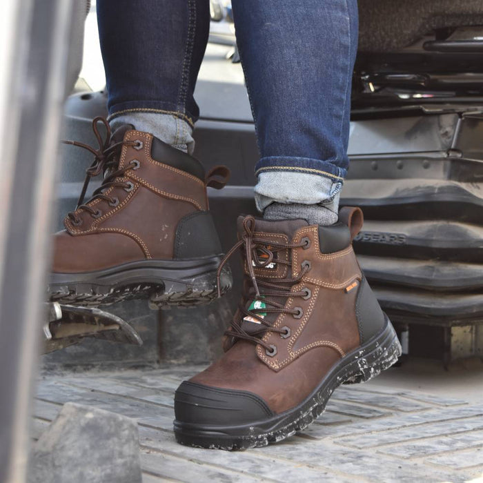 Brown work boots with black soles worn by a person, standing on a vehicle's step.